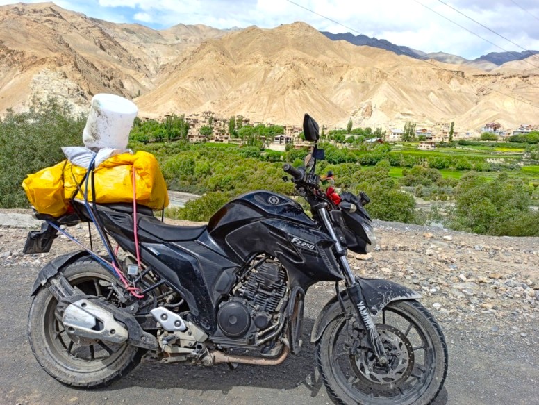bike fully loaded with luggage parked on a rugged mountain road, ready for an adventurous Delhi to Leh bike trip.