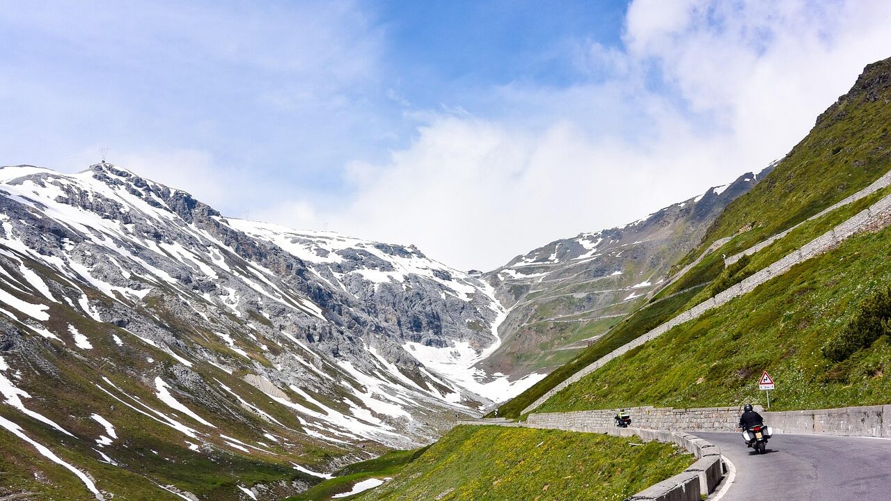 Snow patches along the winding mountain road at Rohtang Pass in Himachal Pradesh during early July, with misty clouds and melting ice under monsoon skies.