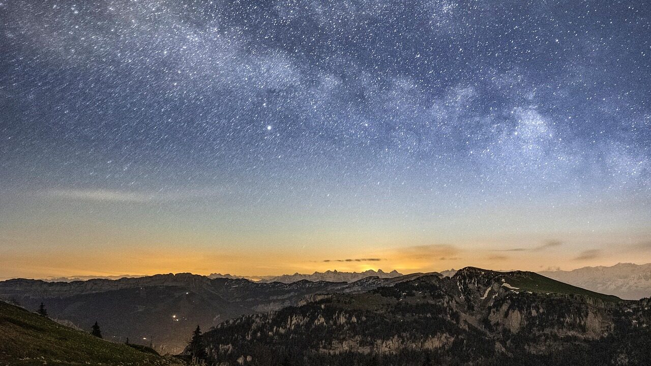 Star-filled night sky over the pine-covered hills and paddy fields of Ziro Valley in Arunachal Pradesh, India.