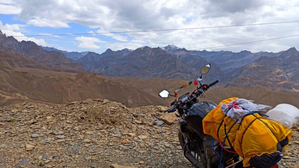 Fully loaded bike with jerry cans parked on a rugged road in Ladakh during a high-altitude journey